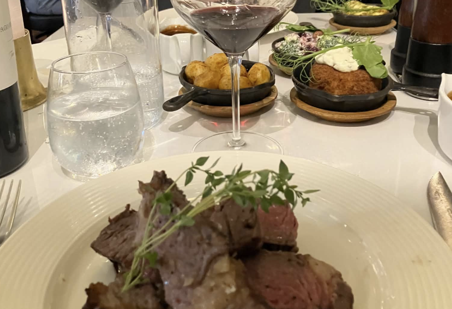 Steak med kartofler og tilbehør på MEAT i Aalborg med rødvin og vand på bordet.
