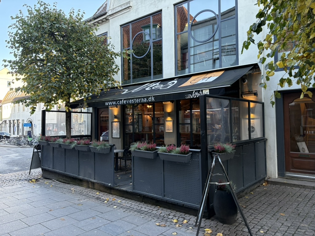 Café Vesterå i Aalborg centrum med udendørs servering, sorte markiser og hyggelig terrasse langs gågaden.