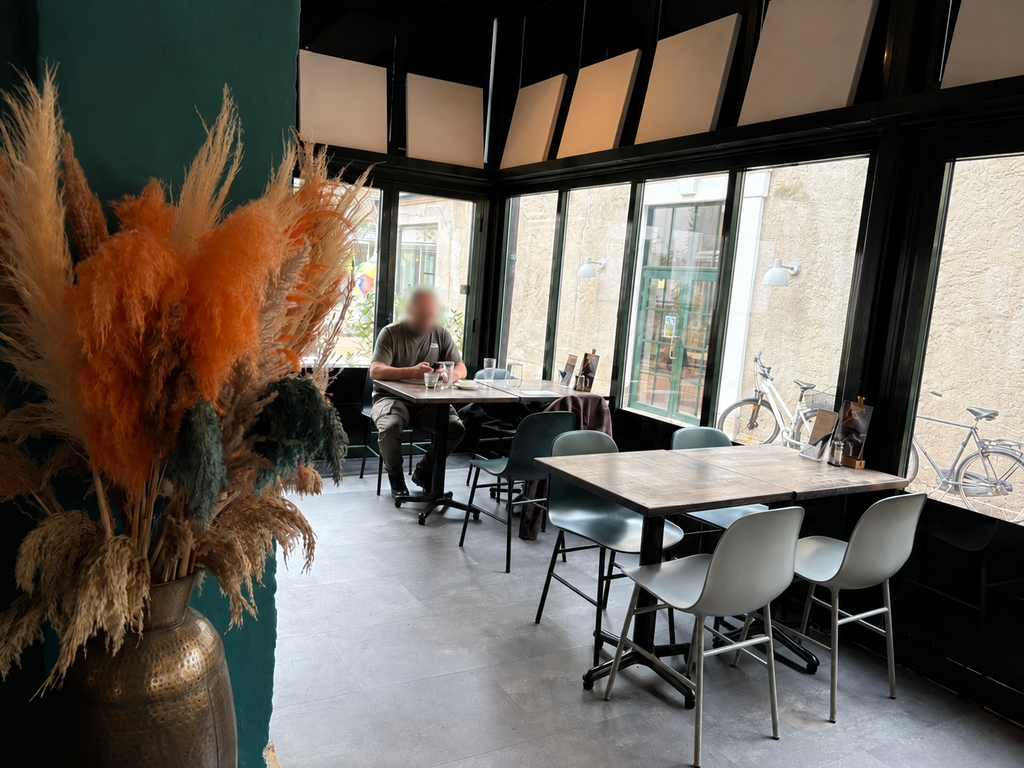 Hyggelig indretning hos Café Chino i Odense med store vinduespartier, moderne møbler og udsigt til Brandts Passage.