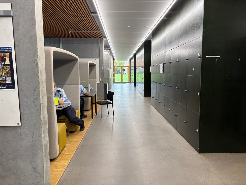 Politistuderende og undervisere arbejder ved studiepladser på gangen på Politiskolen i Brøndby.